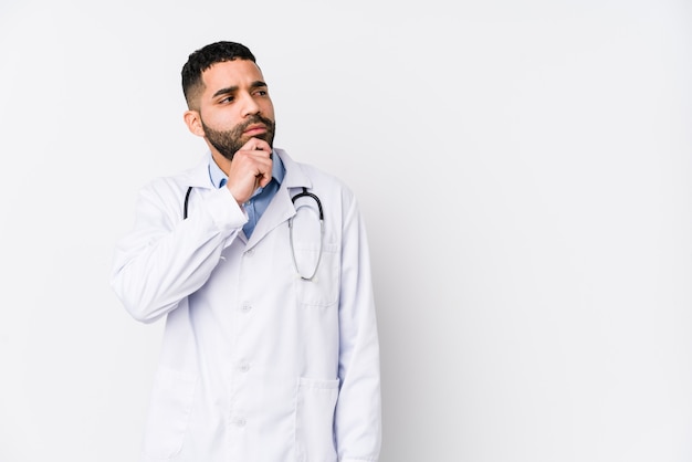 Young doctor man looking sideways with doubtful and skeptical expression