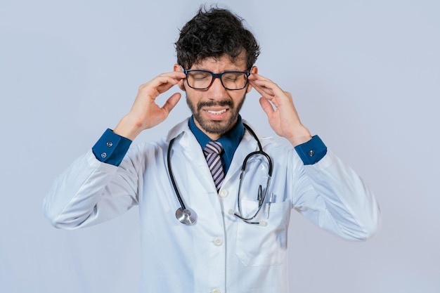 Young Doctor suffering with headache isolated Doctor with migraine holding his head Fatigued doctor with headache isolated