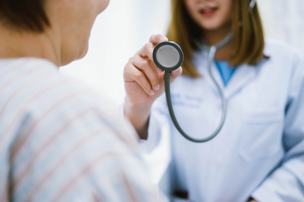 Young doctor using stethoscope to exam senior patient heart