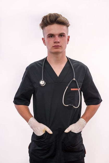 Young doctor with stethoscope in dark medical uniform posing isolated on white