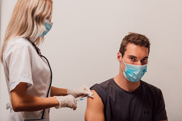 Young doctor woman makes an injection vaccination to the patient in the arm