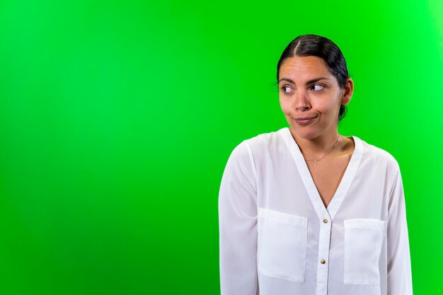 Young doubtful woman green background