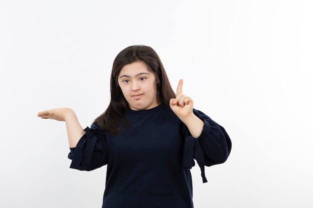 Young down syndrome girl in black sweater standing over white.