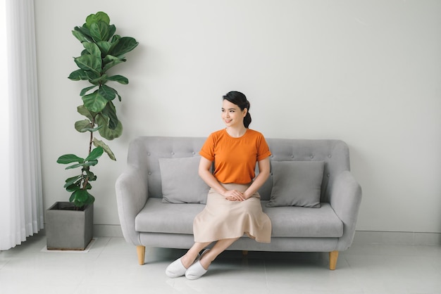 Young dreaming woman sitting on sofa at home