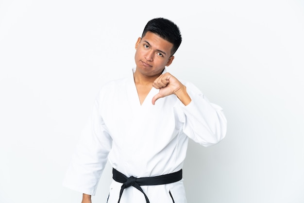 Young Ecuadorian man doing karate isolated on white background showing thumb down with negative expression