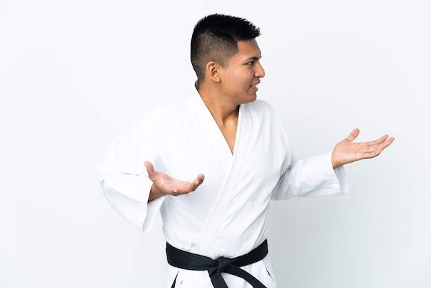 Young Ecuadorian man doing karate isolated on white wall with surprise expression while looking side