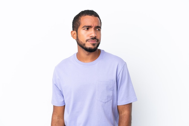 Young Ecuadorian man isolated on white background having doubts while looking side