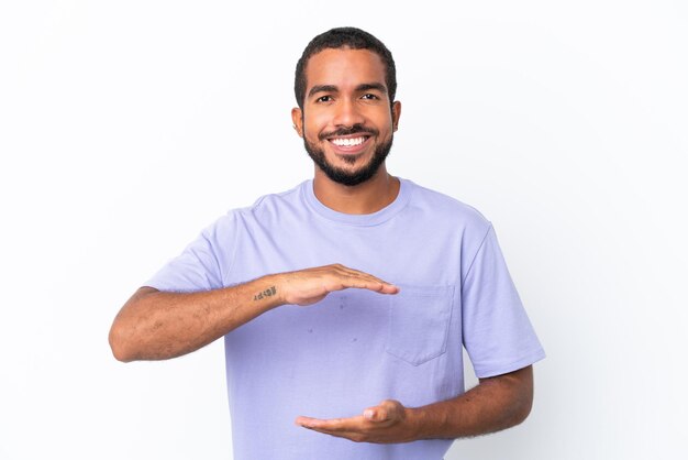 Young Ecuadorian man isolated on white background holding copyspace imaginary on the palm to insert an ad