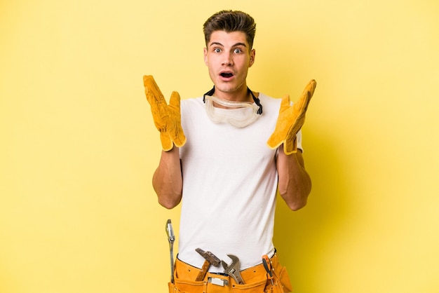 Young electrician caucasian man isolated on yellow background surprised and shocked