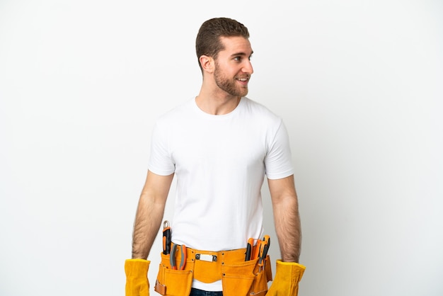 Young electrician man isolated white wall looking to the side and smiling