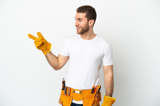 Young electrician man over isolated white wall pointing finger to the side and presenting a product