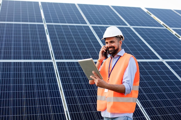 The young electrician works at a solar station using gadgets