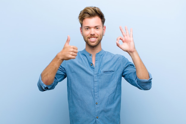 young elegant guy showing okay and thumbs-up gestures smiling