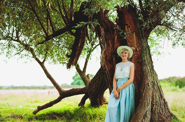 Young elegant happy woman in white hat in the field walking, smiling. Vintage clothes. Autumn season