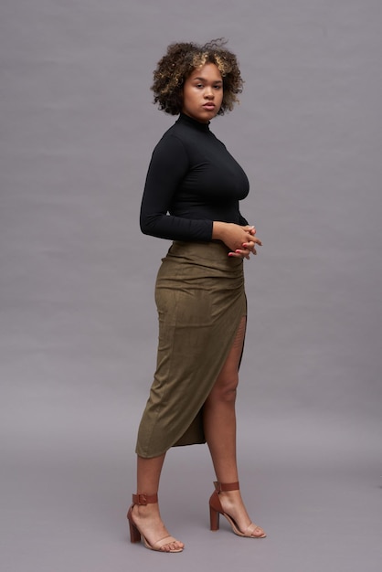 Young elegant intercultural woman in black turtleneck and long brown skirt