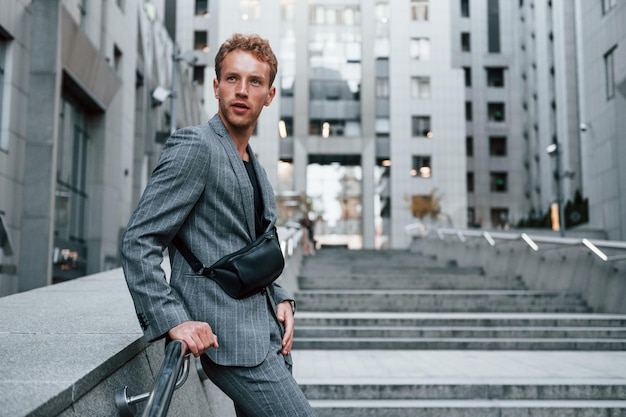 Young elegant man in good clothes is outdoors in the city at daytime