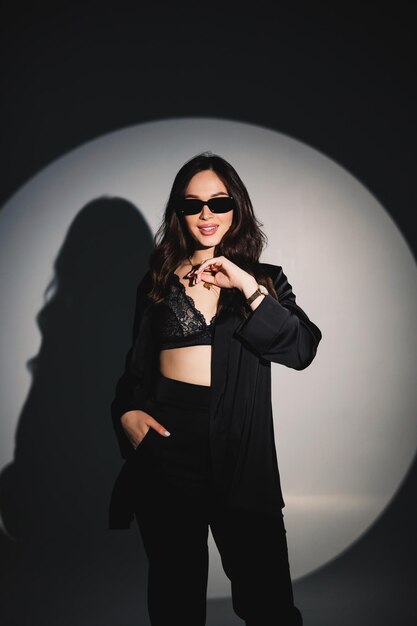 Young elegant stylish woman in a black suit Studio shot A woman in a black suit and black glasses on a white background