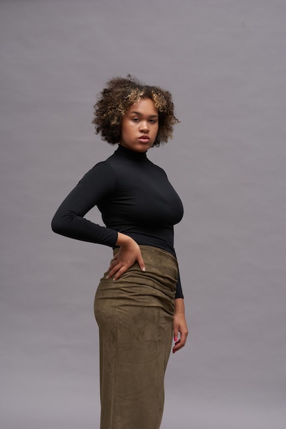 Young elegant woman in classy black turtleneck and long khaki skirt