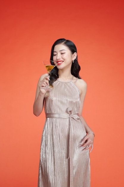 Young elegant woman in glitter dress holding glass of champagne and celebrating