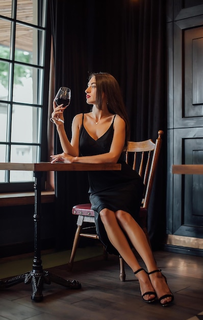 Young elegant woman hold glass of red wine indoor shot selective focus