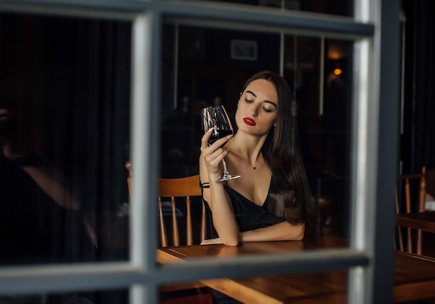 Young elegant woman hold glass of red wine indoor shot selective focus