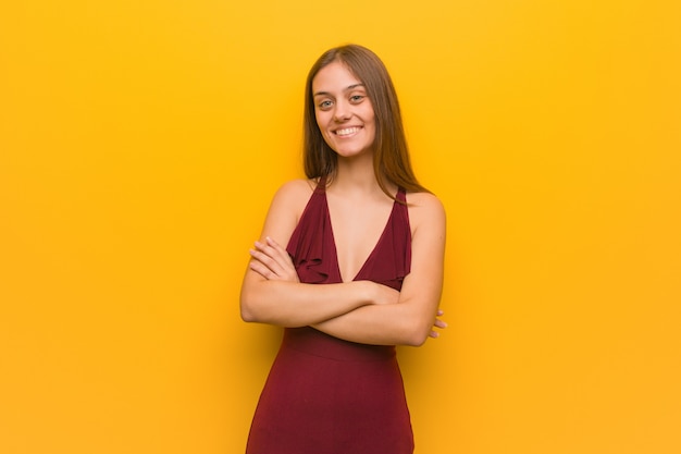 Photo young elegant woman wearing a dress crossing arms, smiling and relaxed