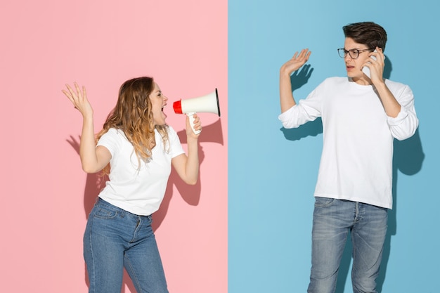 Young emotional man and woman on pink and blue background