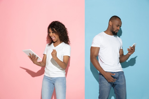 Young emotional man and woman on pink and blue background