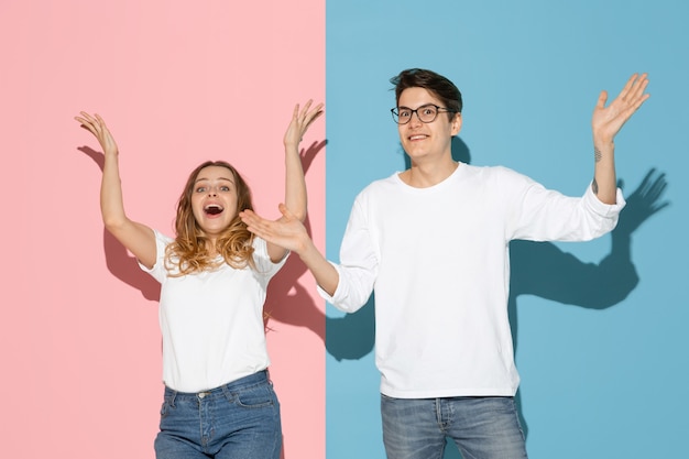 Young emotional man and woman on pink and blue background