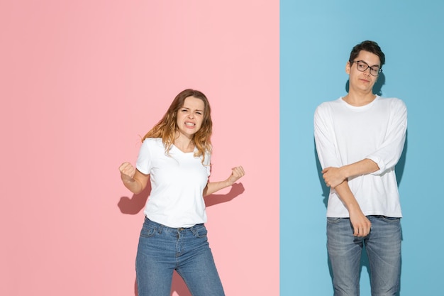 Young emotional man and woman on pink and blue background