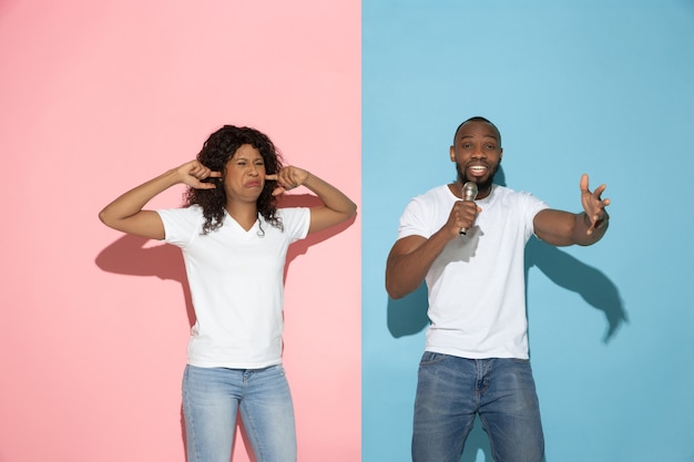 Young emotional man and woman on pink and blue