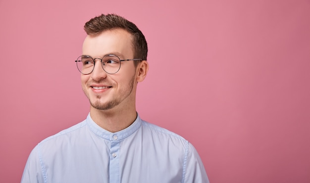 A young employee in a sky blue shirt stands on pink