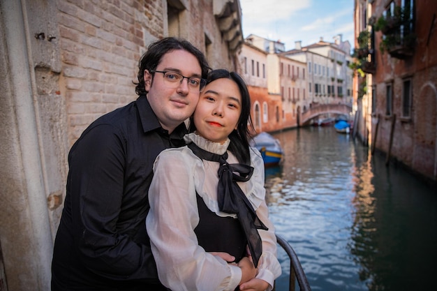 Young engaged couples standing by the canal hugging each other look in the same direction