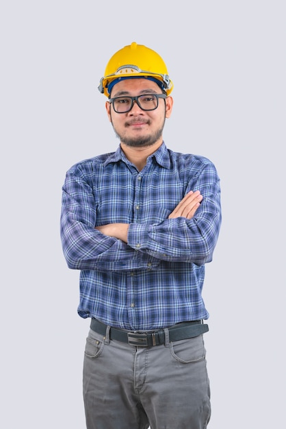 Young engineer asian man wearing long sleeve striped shirts with arms crossed and yellow hard hat