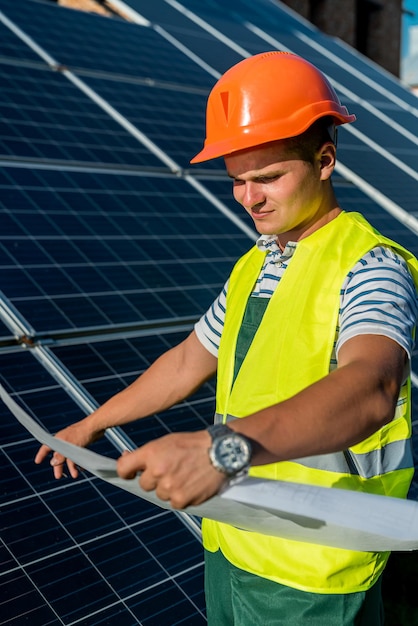 Young engineer near solar panel and worker holding blueprint photovoltaic