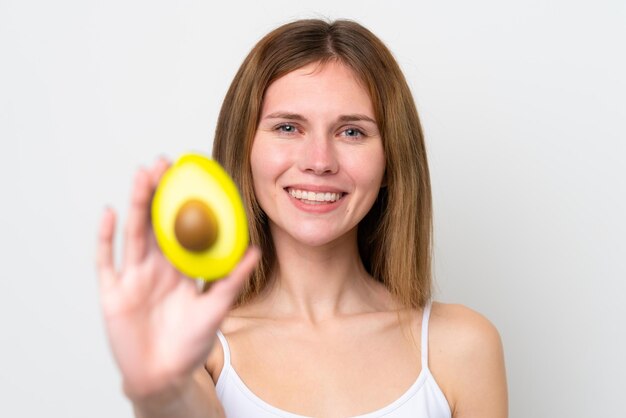 Young English woman holding an avocado while smiling Close up portrait