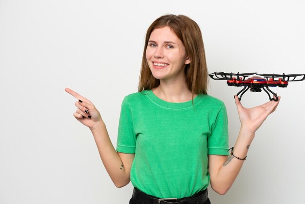 Young English woman holding a drone isolated on white background pointing finger to the side