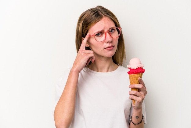 Young English woman holding an ice cream isolated on white background pointing temple with finger thinking focused on a task