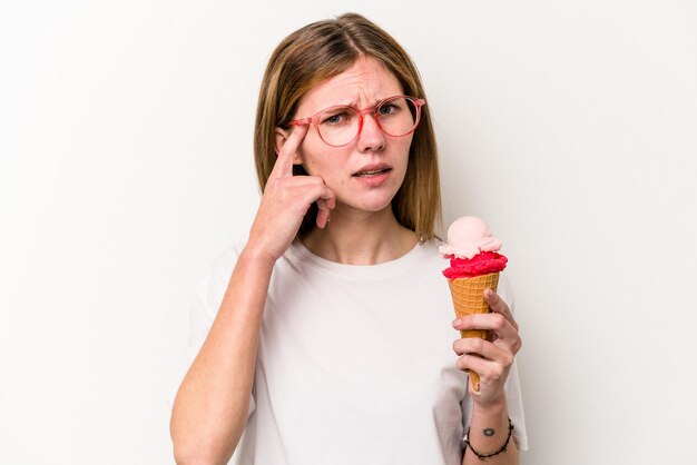 Young English woman holding an ice cream isolated on white background showing a disappointment gesture with forefinger