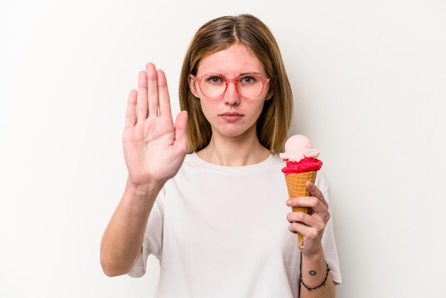 Young English woman holding an ice cream isolated on white background standing with outstretched hand showing stop sign, preventing you.