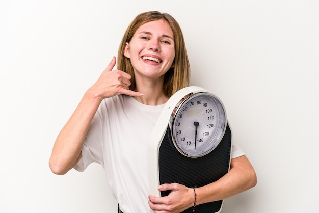 Young English woman holding a scale isolated on white background showing a mobile phone call gesture with fingers