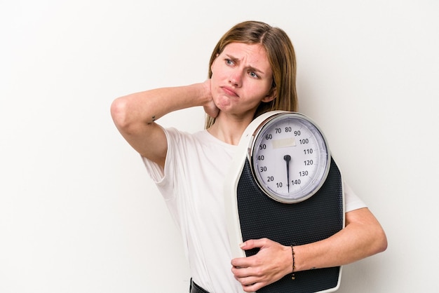 Young English woman holding a scale isolated on white background touching back of head thinking and making a choice