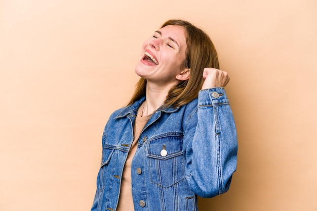 Young English woman isolated on beige background celebrating a victory passion and enthusiasm happy expression