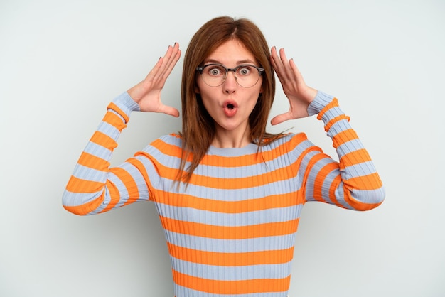 Young English woman isolated on blue background celebrating a victory or success, he is surprised and shocked.