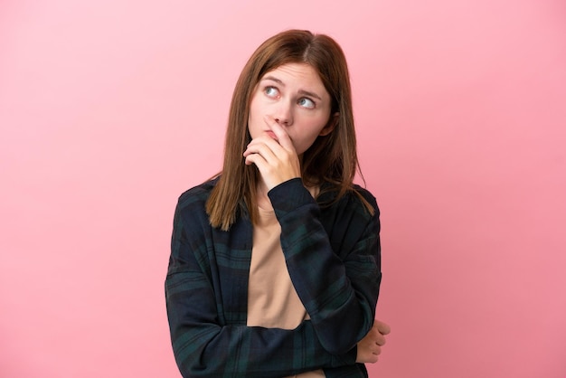 Young English woman isolated on pink background having doubts and with confuse face expression