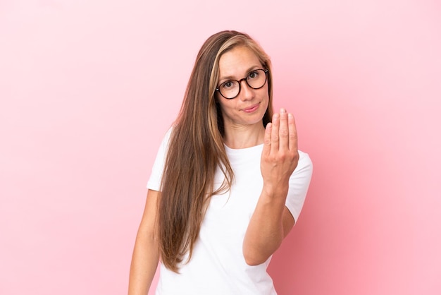 Young English woman isolated on pink background inviting to come with hand. Happy that you came