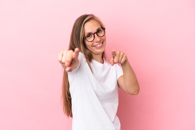 Young English woman isolated on pink background pointing front with happy expression