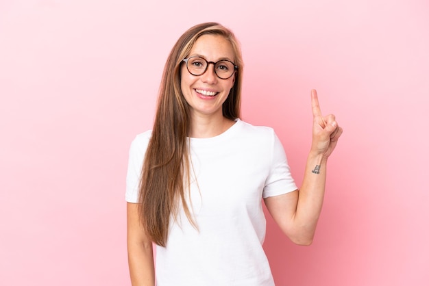 Young English woman isolated on pink background showing and lifting a finger in sign of the best