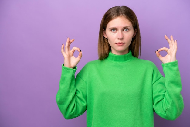 Young English woman isolated on purple background in zen pose