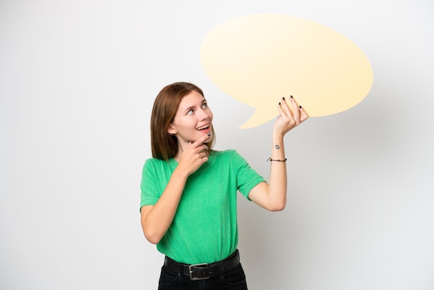 Young English woman isolated on white background holding an empty speech bubble and pointing it